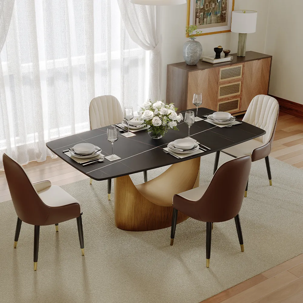 Rectangular sintered stone dining table with a bronze base, styled in a bright contemporary dining room with neutral chairs.