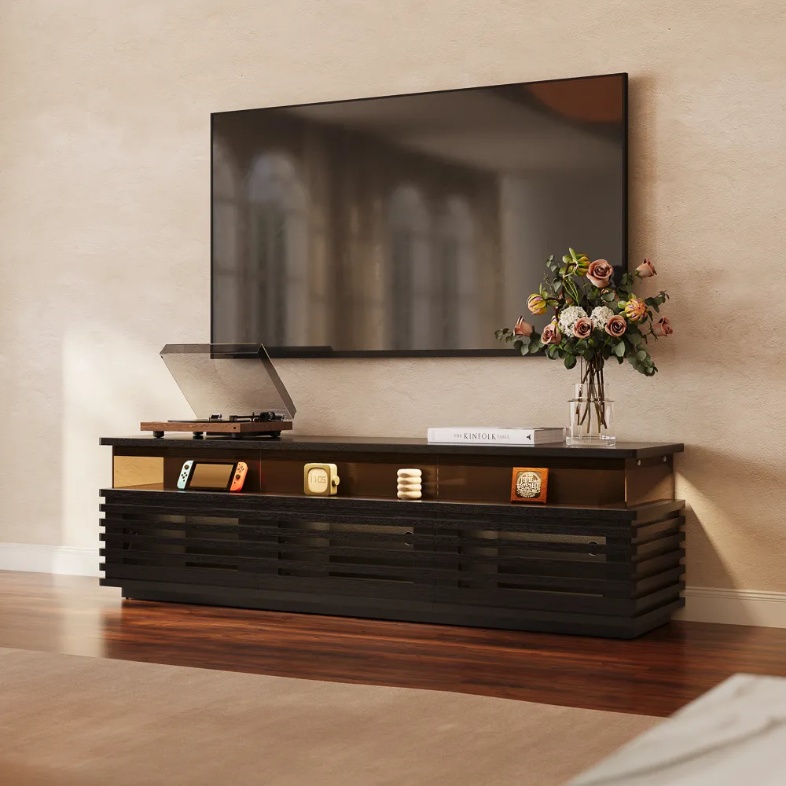 POVISON Selene 71” Horizontal Slatted TV Stand with Adjustable LED Lights in black with storage and a disc player, a flower, a book on top and a handheld game console and decorations in its shelf in a warm and bright living room