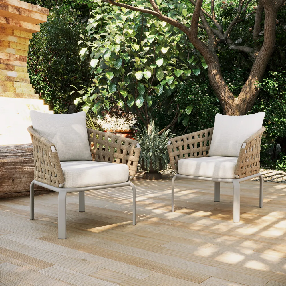 A cushioned wicker lounge chair beside a slim side table, styled with a book, lantern, and compact balcony plants.