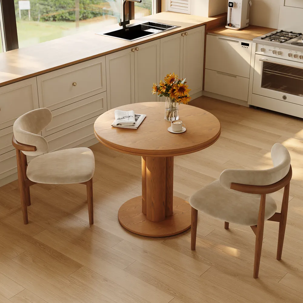 Warm walnut round dining table with a pedestal base, styled in a compact dining corner for two to four everyday meals.