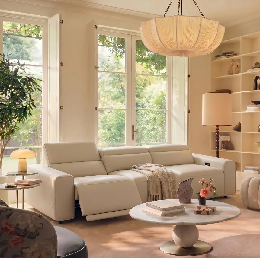 Bright living room with a cream reclining sofa, round coffee table, and large windows
