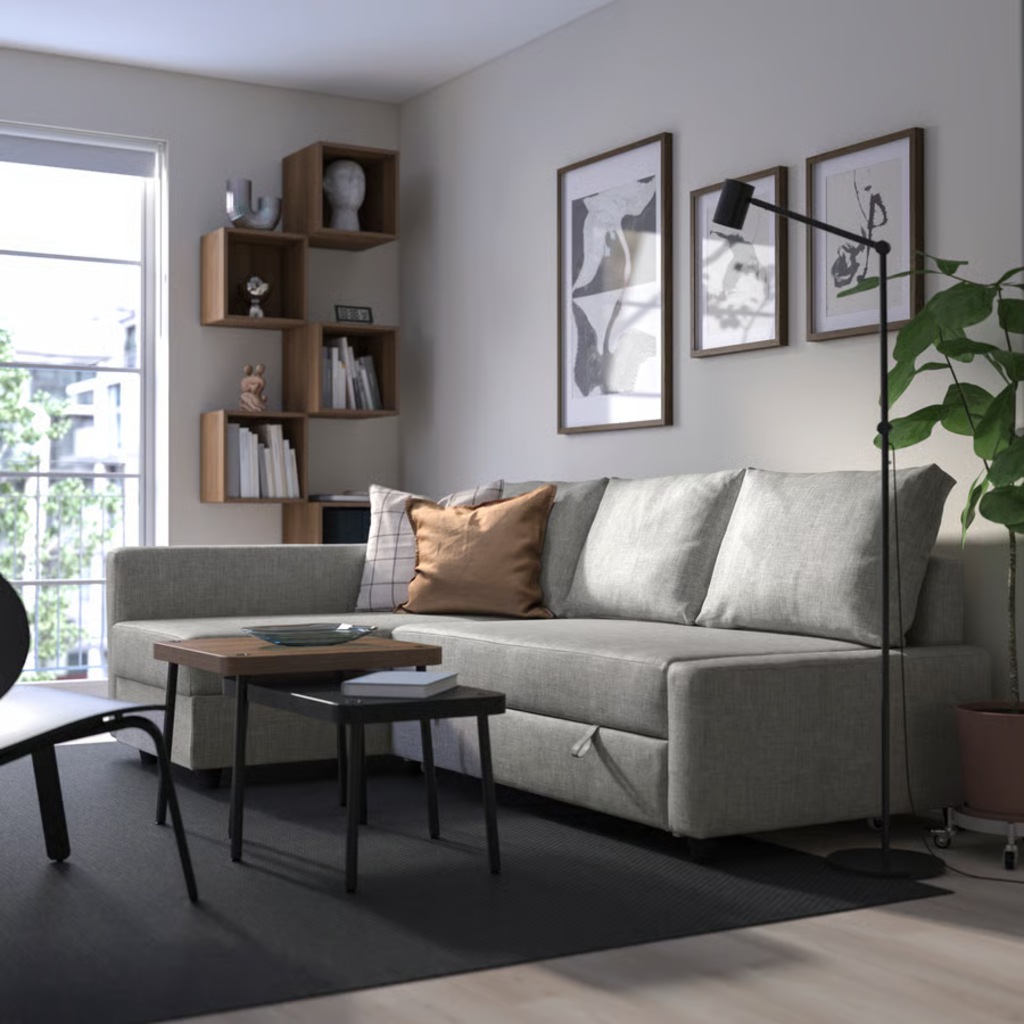 Light gray sleeper sofa in a modern living room with wood tables, wall art, shelving, and a floor lamp.