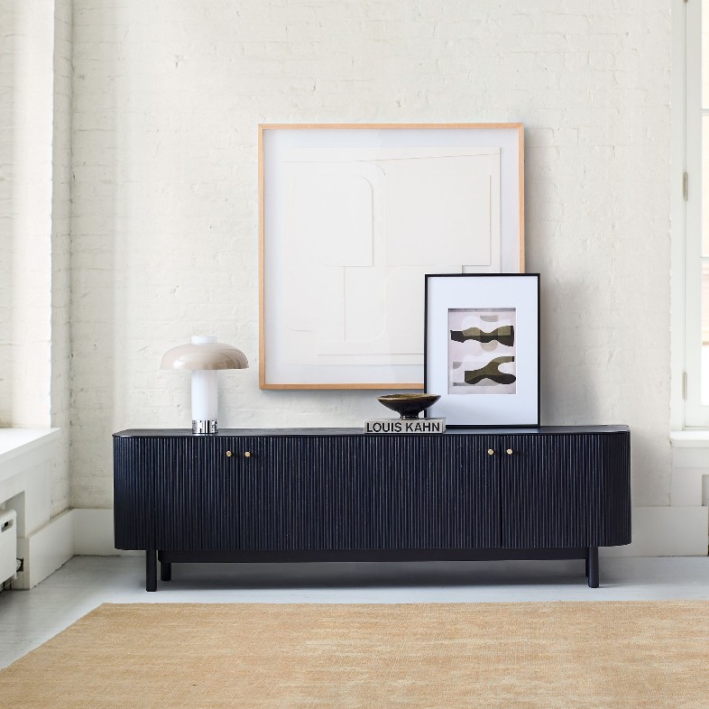 West Elm Ellington Black Media Console with storage and a lamp, a bowl and paintings on top near a window in a bright and minimalist living room