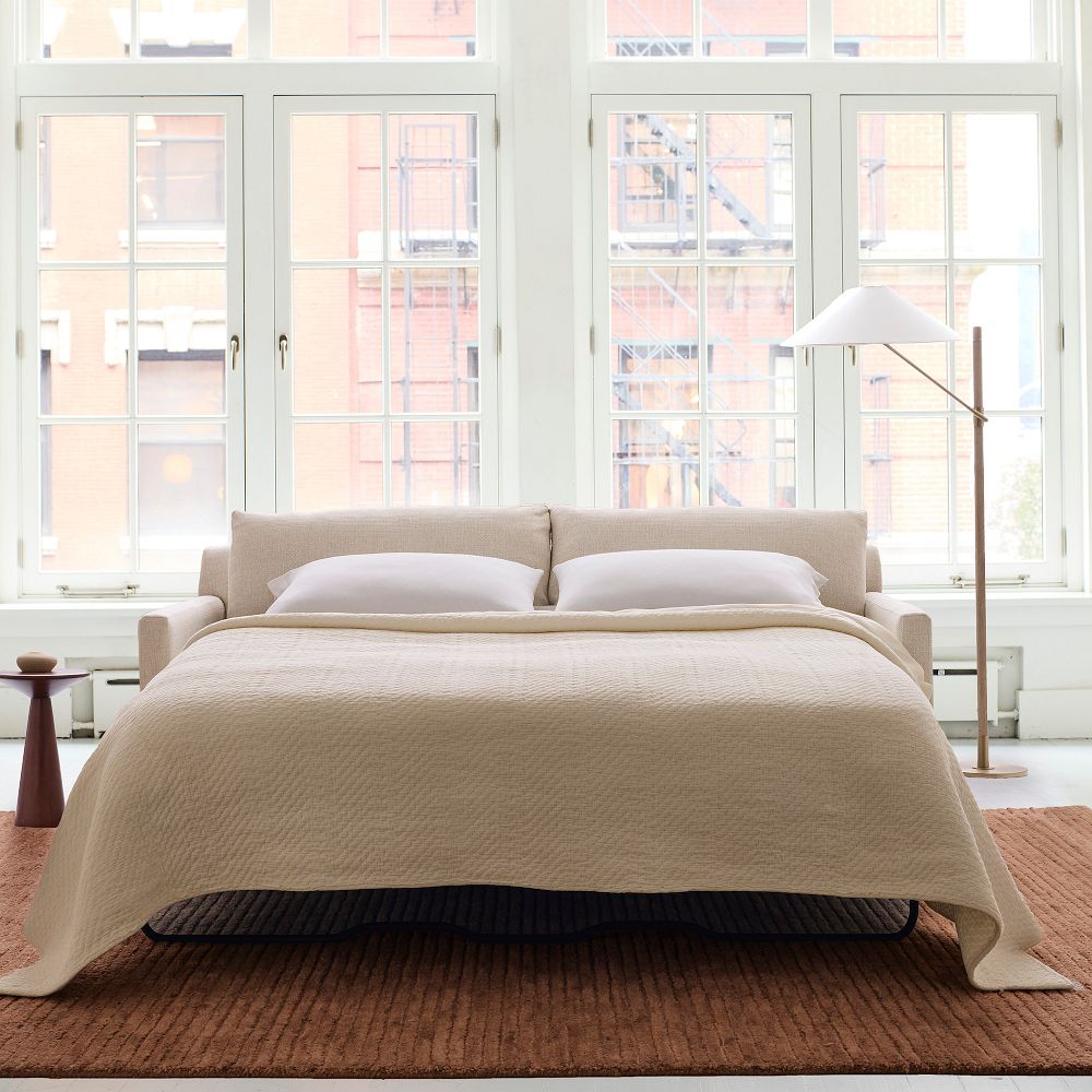 West Elm Marin Sleeper Sofa near a side table and a floor lamp in a bright and minimalist apartment