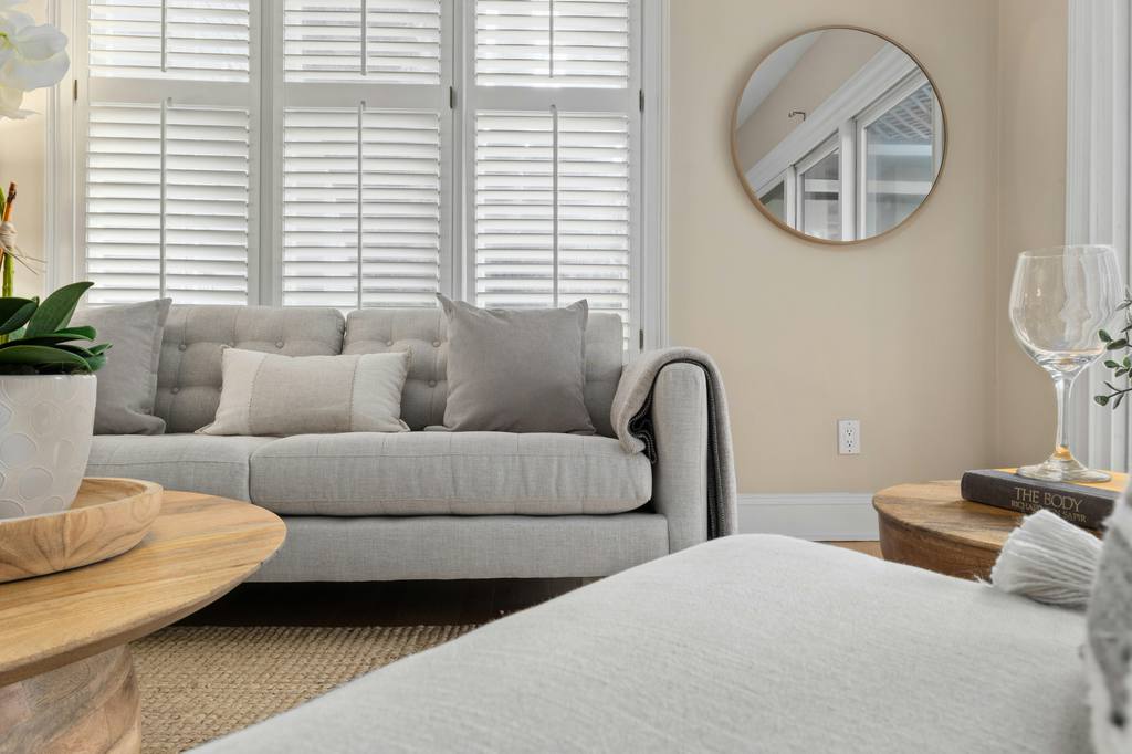a round mirror as a decoration on the wall in a cozy feng shui living room with sofas, side table, coffee table and accent chair