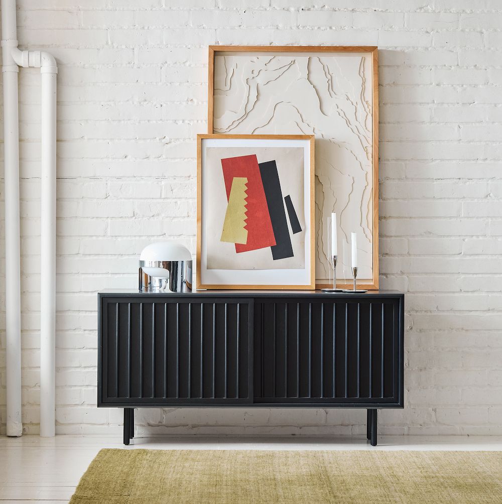 West Elm Slatted Shallow Media Console 48" with storage and paintings and decorations on top in a bright and minimalist living room