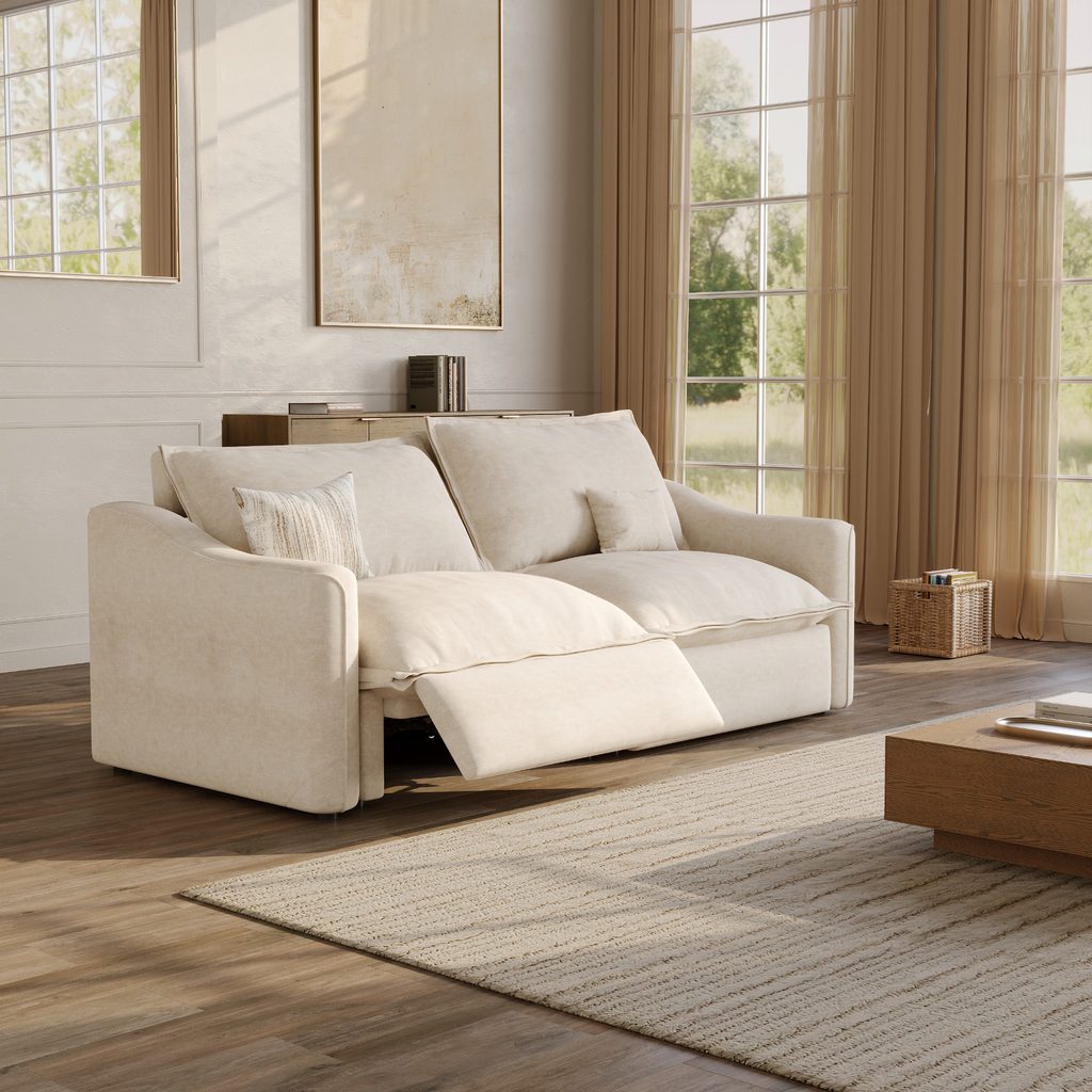 Cream power reclining loveseat sofa with an extended footrest and plush cushions in a bright, sunlit living room.