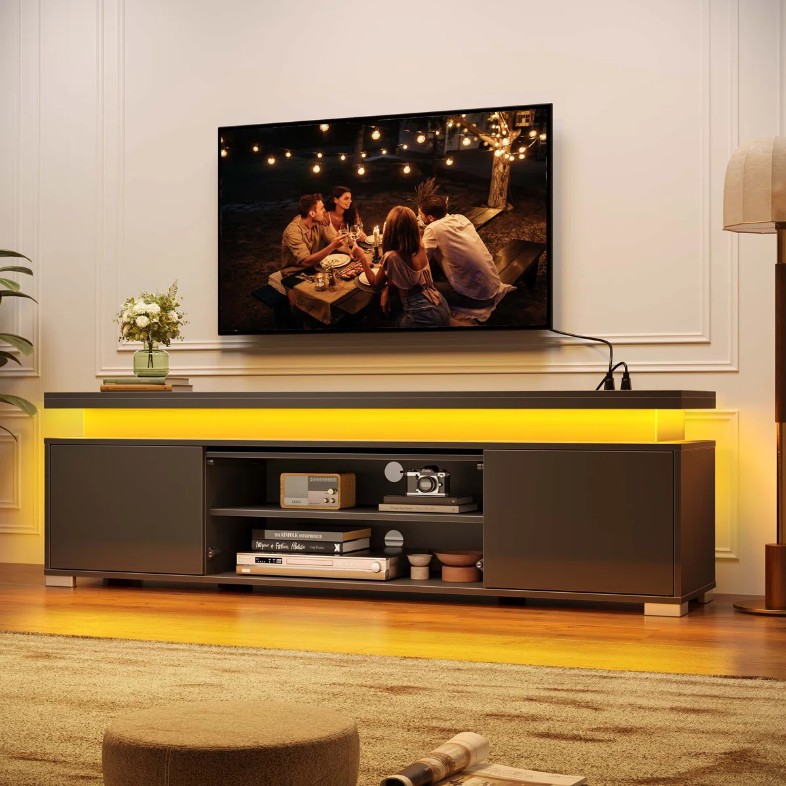 a Wrought Studio RGB LED TV Stand with storage for media and game play near a floor lamp and a plant for movie nights in a warm and cozy living room