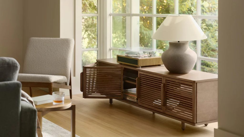 Burrow Opera Media Console with storage for books and a lamp and a disc player on top near a chair and a side table in a bright and cozy living room