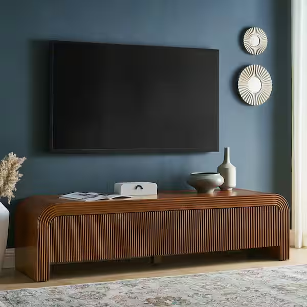 Modway Waterflute 68" Fluted TV Stand with a book, media and decorations on top below a mounted tv near a plant in a bright and modern living room