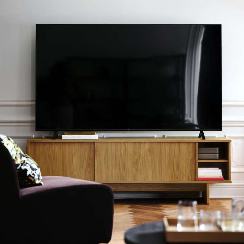 IKEA STOCKHOLM 2025 TV Unit with slide door storage for books and a tv on top near a sofa and a coffee table in a bright and modern living room