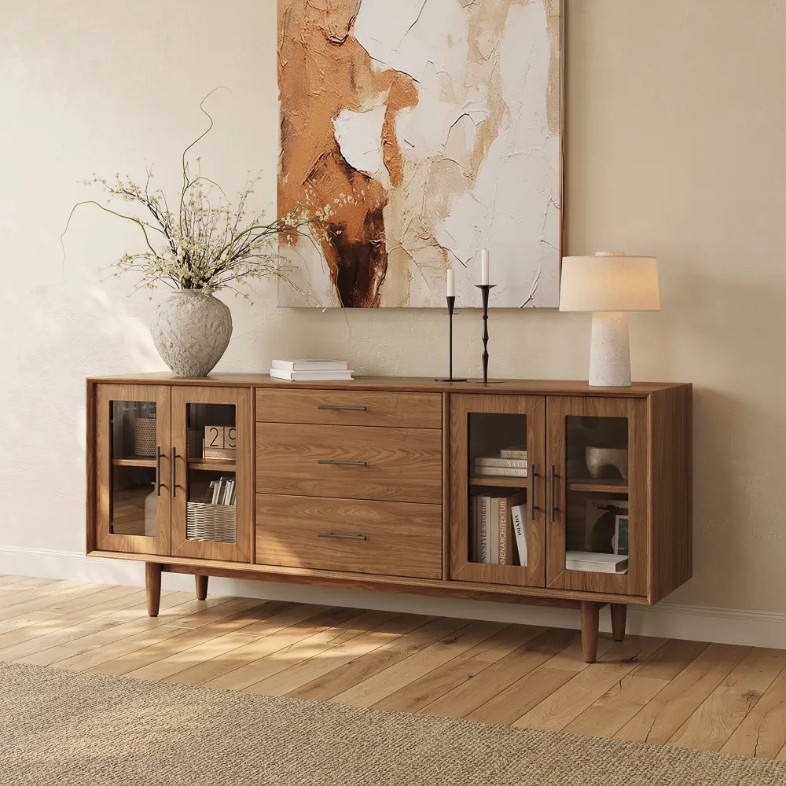Povison 71" Mid-Century Modern TV Stand with Glass Doors and drawers storage for books and a plant, a lamp, books and decorations on top in a warm living room