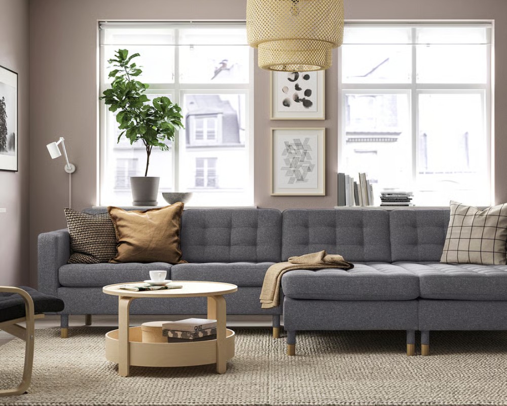 IKEA MORABO L Shaped Sectional near a rectangular oak coffee table and a chair in a bright and compact living room