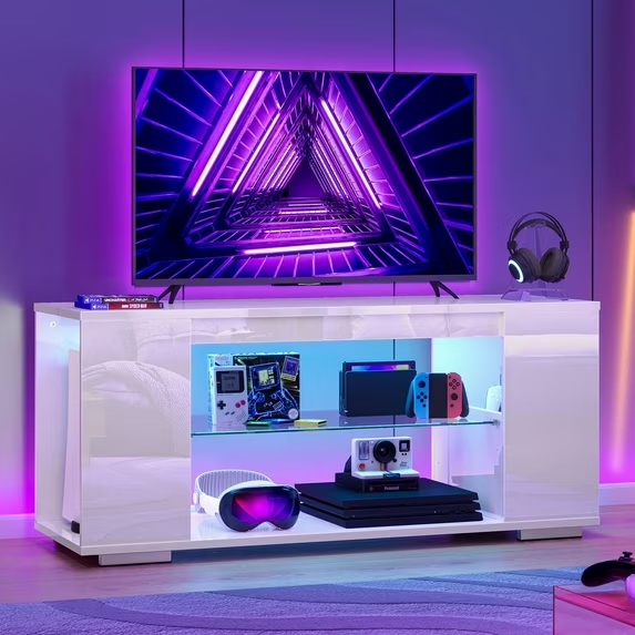 Pinmoco 47'' Gaming Entertainment Center with LED Lights and storage for gamepod, game controller, vr device and playstation with a headset and a tv on top in a colorful living room
