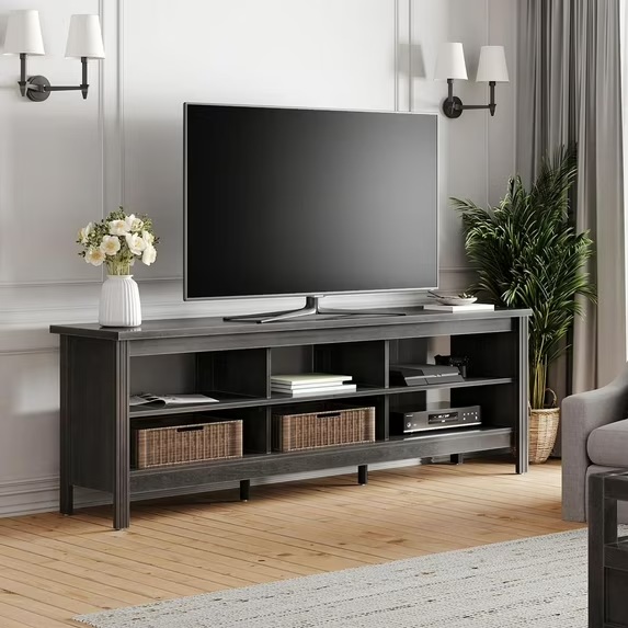 FITUEYES 70'' TV Stand with Open Shelves for media, playstation and storage with a plant, a book and a tv on top near a sofa against a white wall in a modern mid-century living room