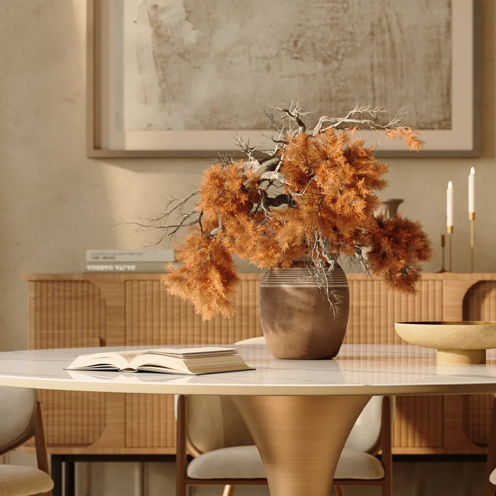 a plant as a decoration in the middle of a round marble dining table with a book and a bowl on top near a console table in a cozy and mid century modern dining room