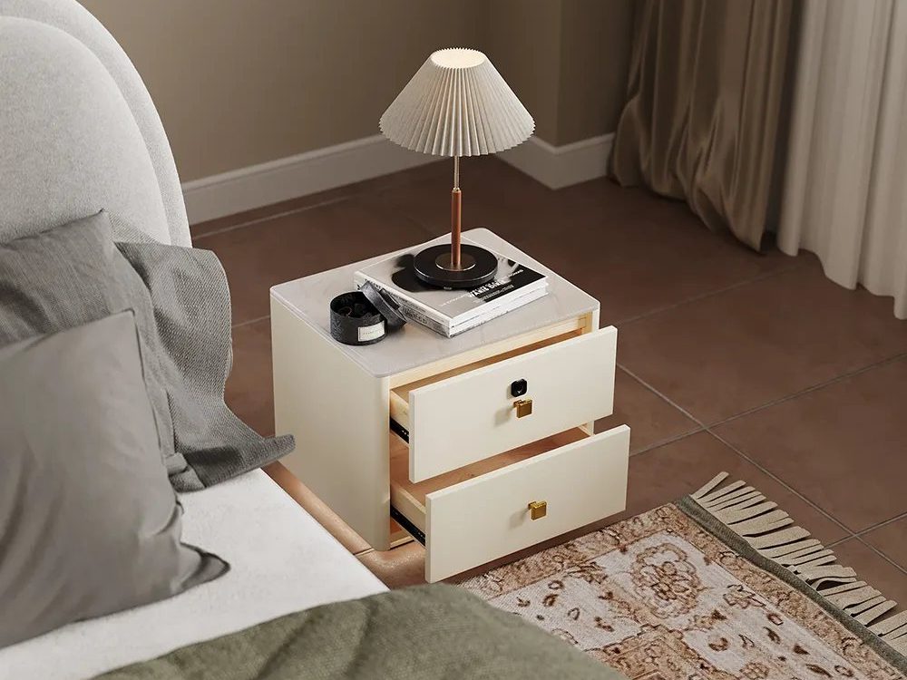 a nightstand with drawers and a lamp and some books on top near a bed in a modern farmhouse bedroom