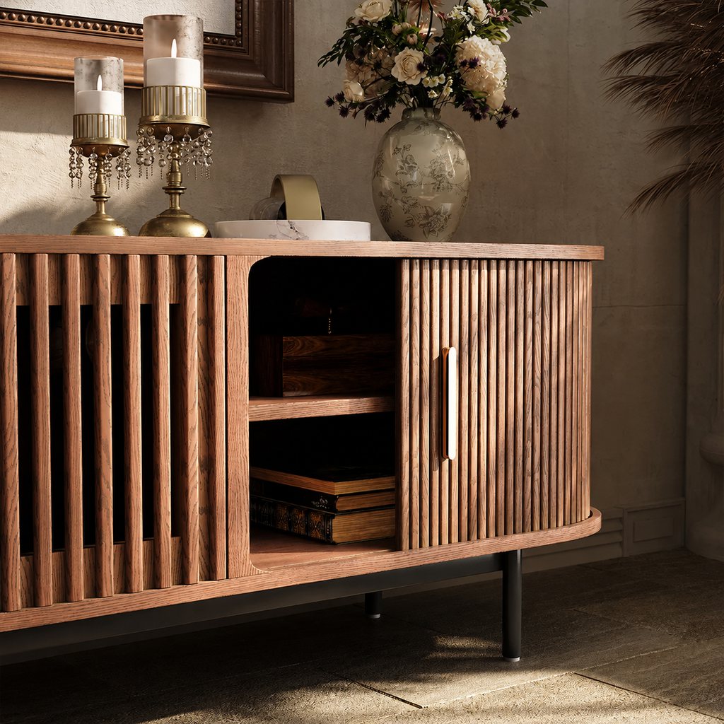 Warm interior with a walnut fluted sideboard, brass candleholders, floral arrangement, and open shelf storage against a textured neutral wall.