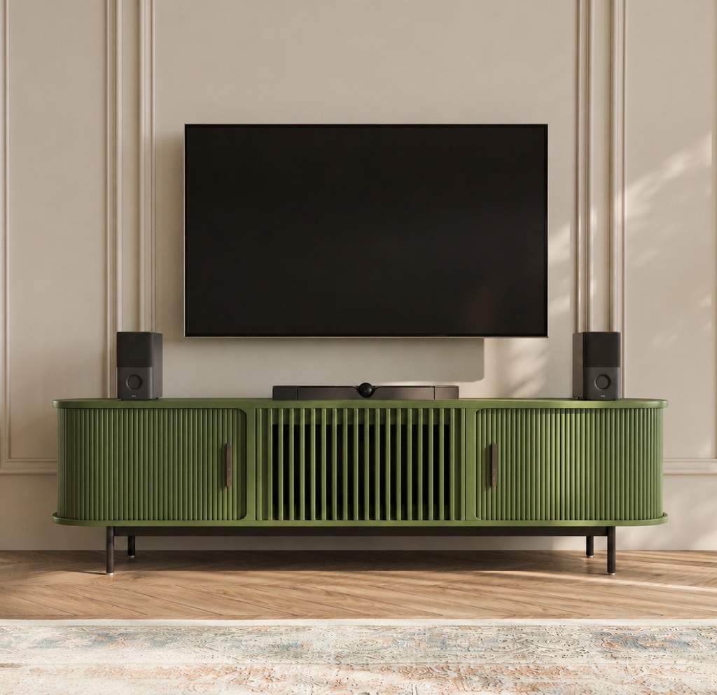 Olive green fluted TV stand beneath a wall-mounted TV, styled with black speakers, neutral wall molding, wood flooring, and a soft patterned rug.