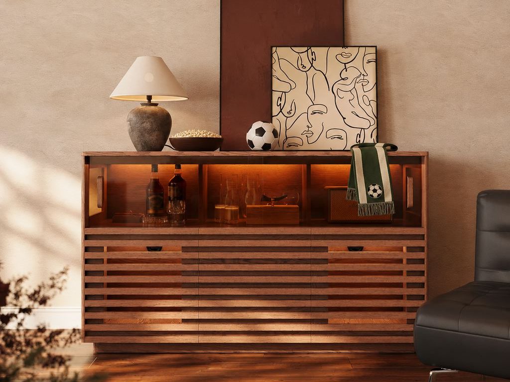 Warm living room with a wood sideboard, subtle soccer watch-party decor, popcorn, a soccer ball, and a green fan scarf beside a black lounge chair.