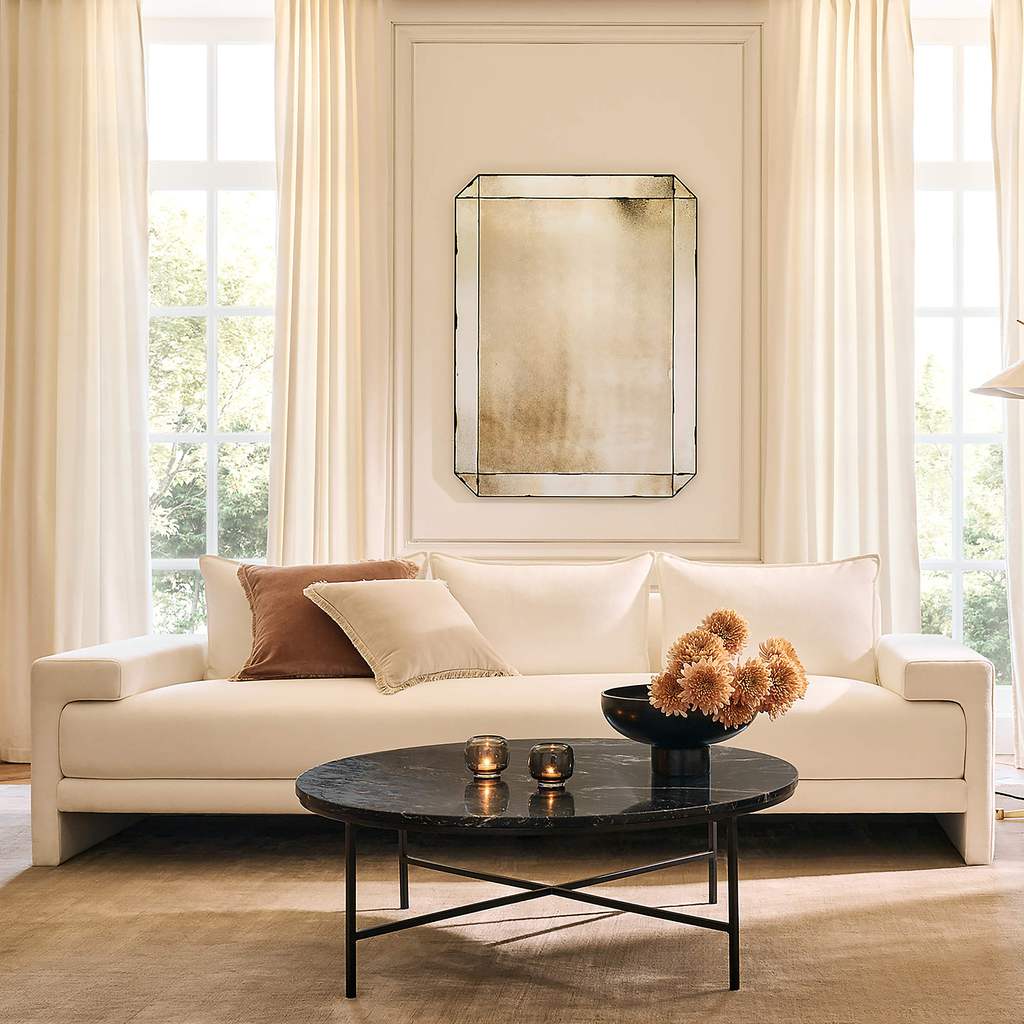 CB2 Camden 81" Apartment Sofa with cushions near a round marble coffee table in a modern and bright living room