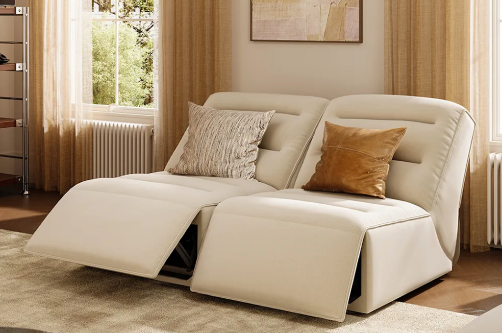 Stylish off-white fabric power lift recliners configured as a double seating lounge couch with extended footrests.