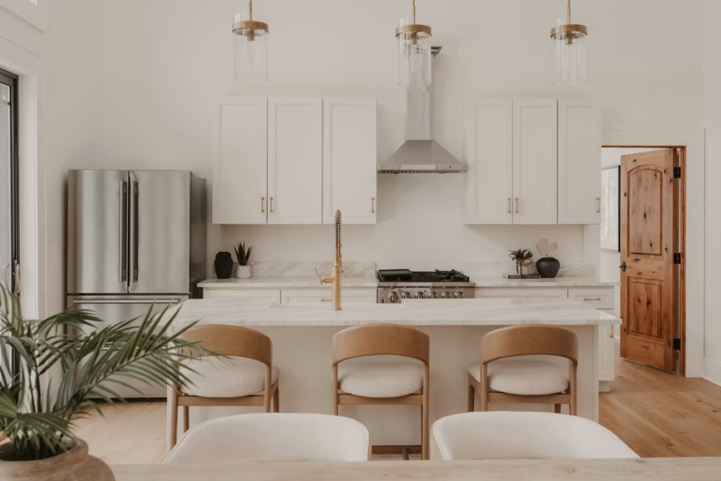 Stylish light wooden bar stools with white upholstered seats set against a minimalist marble kitchen island.
