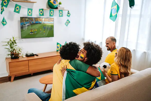 Friends of soccer fans watch world cup on TV at home, sitting on a comfortable sofa