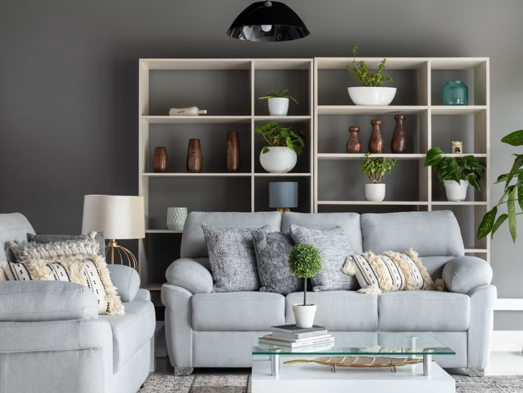 Contemporary light grey fabric loveseat sofa for small spaces against a dark grey accent wall with open shelving.