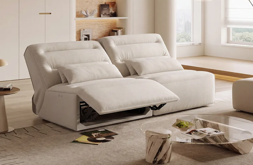 A white leather double seater power recliner sofa showcasing one side fully reclined over a soft carpet rug.