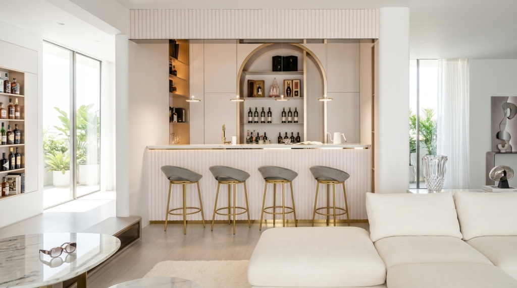 Elegant gold metal bar stools with plush grey velvet seats placed along a premium, modern home bar counter.