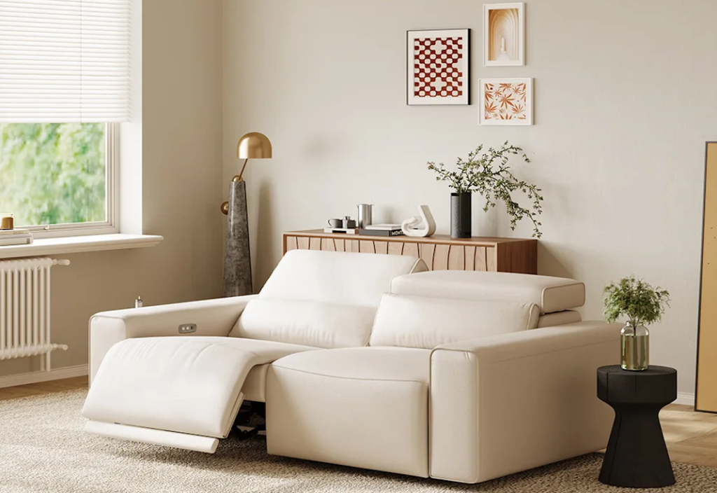 Sleek off-white leather power reclining loveseat with one side fully extended in a bright beige room.