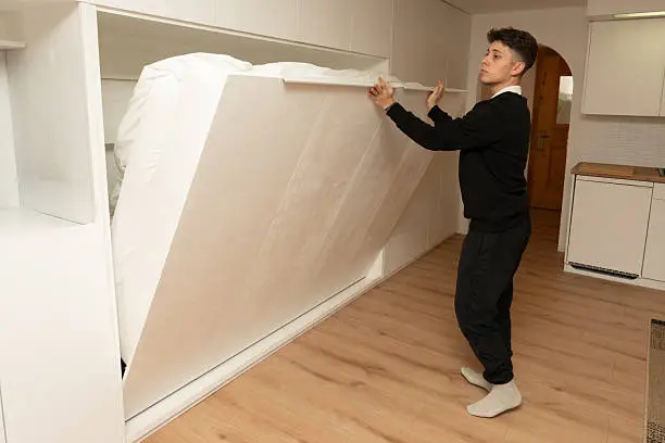 a man pulling out a murphy bed