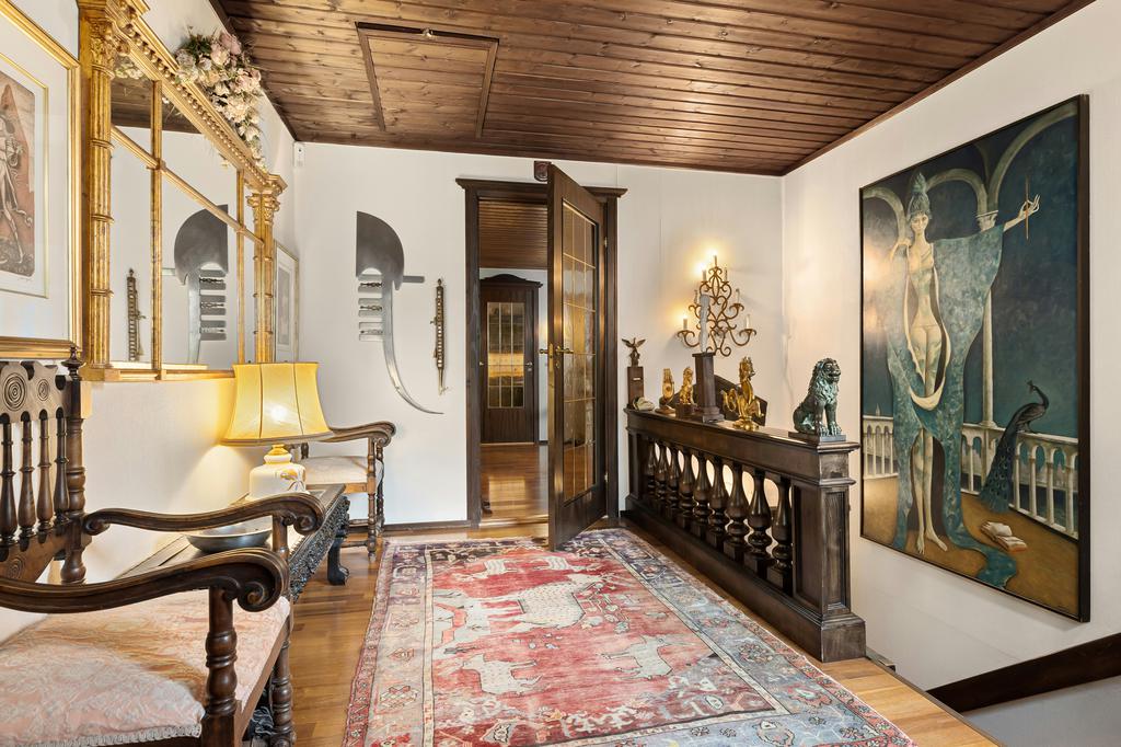 Vintage hallway with red patterned runner rug, wood ceiling, antique bench, gold mirror, framed artwork, and dark wood console decor.