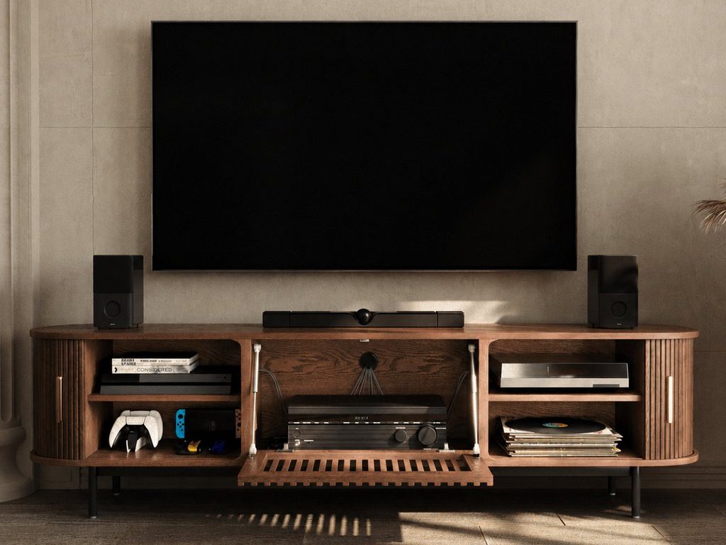 Wall-mounted TV above a walnut tambour door media console with speakers, gaming controllers, vinyl records, and open AV storage.