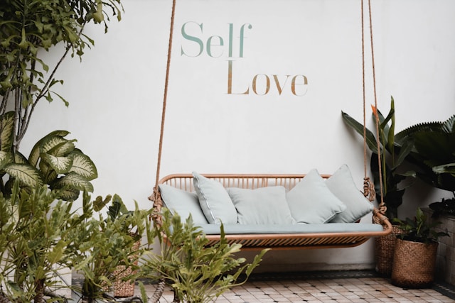 Outdoor swing sofa surrounded by lush plants and cushions, suggesting shaded patio conditions where mildew and organic stains may develop on covers.