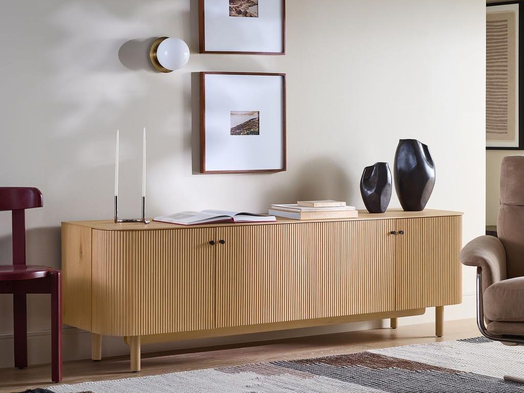 West Elm Ellington Media Console with some books, two candles and decorations on top near a wood chair and an accent chair in a modern living room