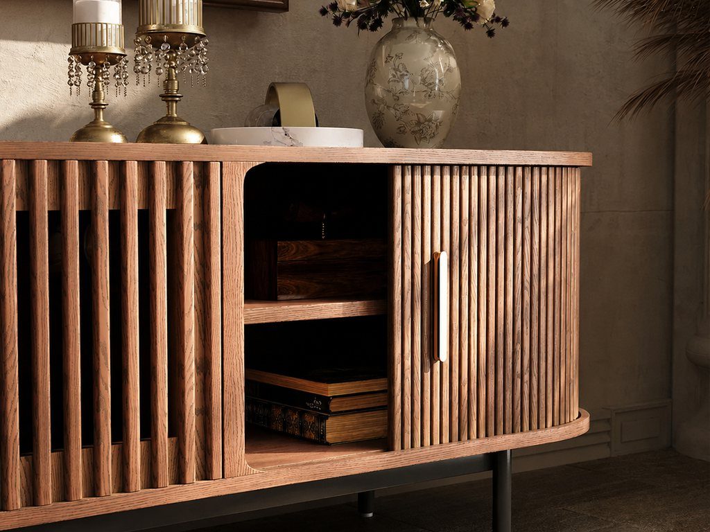 Warm wood fluted media console with brass candles, floral vase, open shelving, and classic decorative accents in a traditional-style interior.