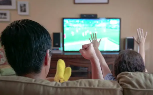 family watching sports on tv, sitting on a reclining sofa