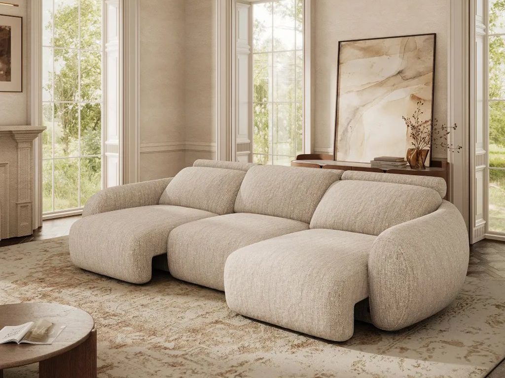 Oversized beige power sleeper sofa with extended seats in an elegant living room featuring tall windows, a patterned rug, and a round wood coffee table.