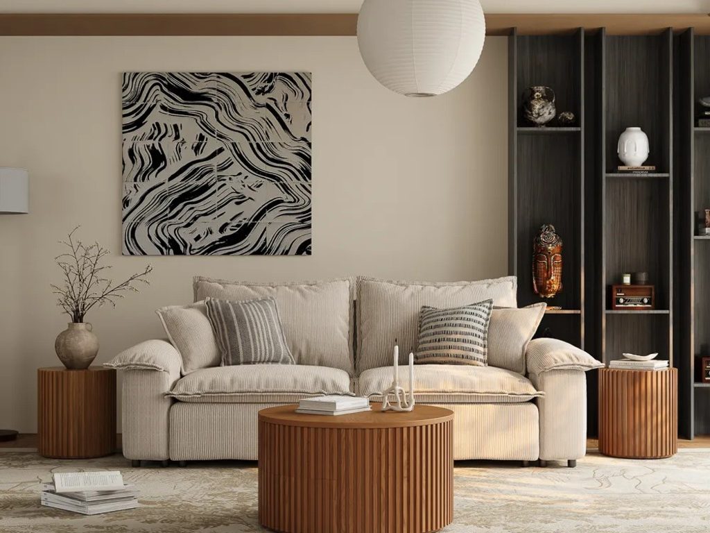 Warm modern living room with a cream sofa, round fluted wood coffee table, matching side tables, abstract wall art, built-in shelving, and a large neutral rug.