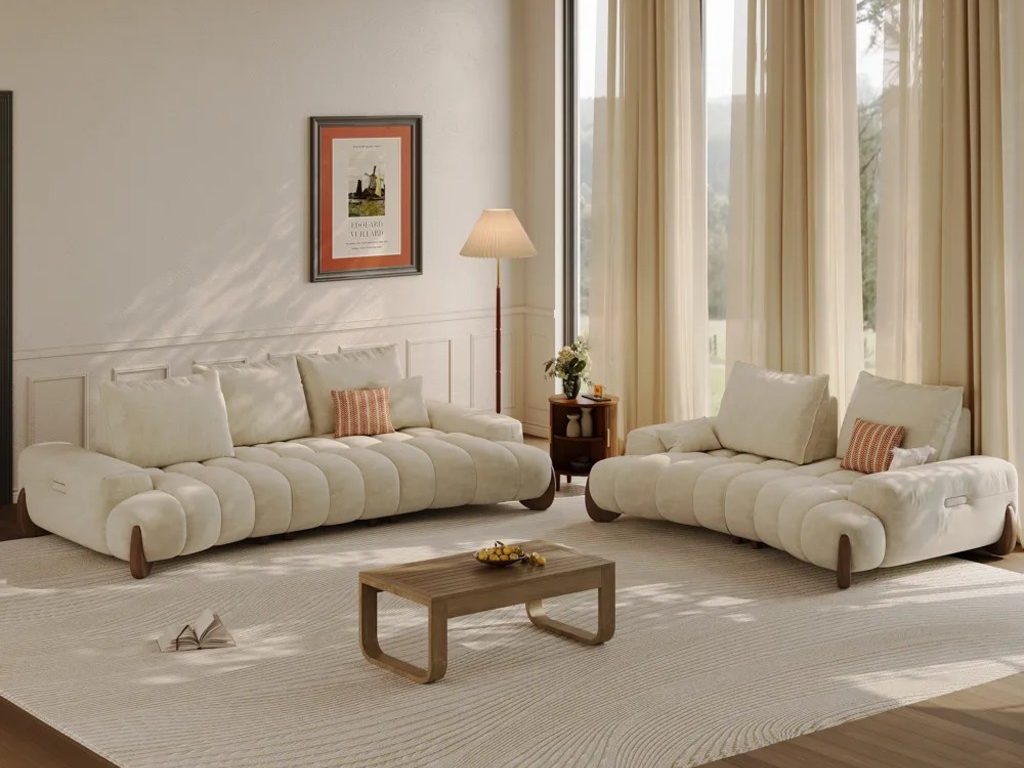 Warm minimalist living room with cream modular sofas, wood coffee table, large neutral area rug, tall curtains, and soft natural light.