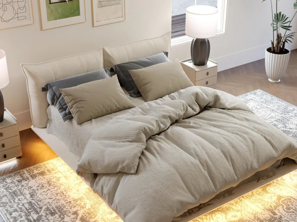 Cozy bedroom with beige upholstered bed, layered neutral bedding, patterned area rug, warm under-bed lighting, bedside lamps, wall art, and indoor plant.