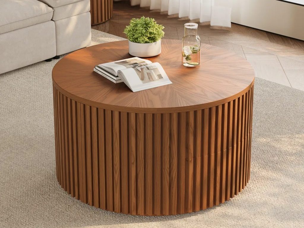 Round fluted wood coffee table on a textured rug beside a light beige sofa in a bright living room.