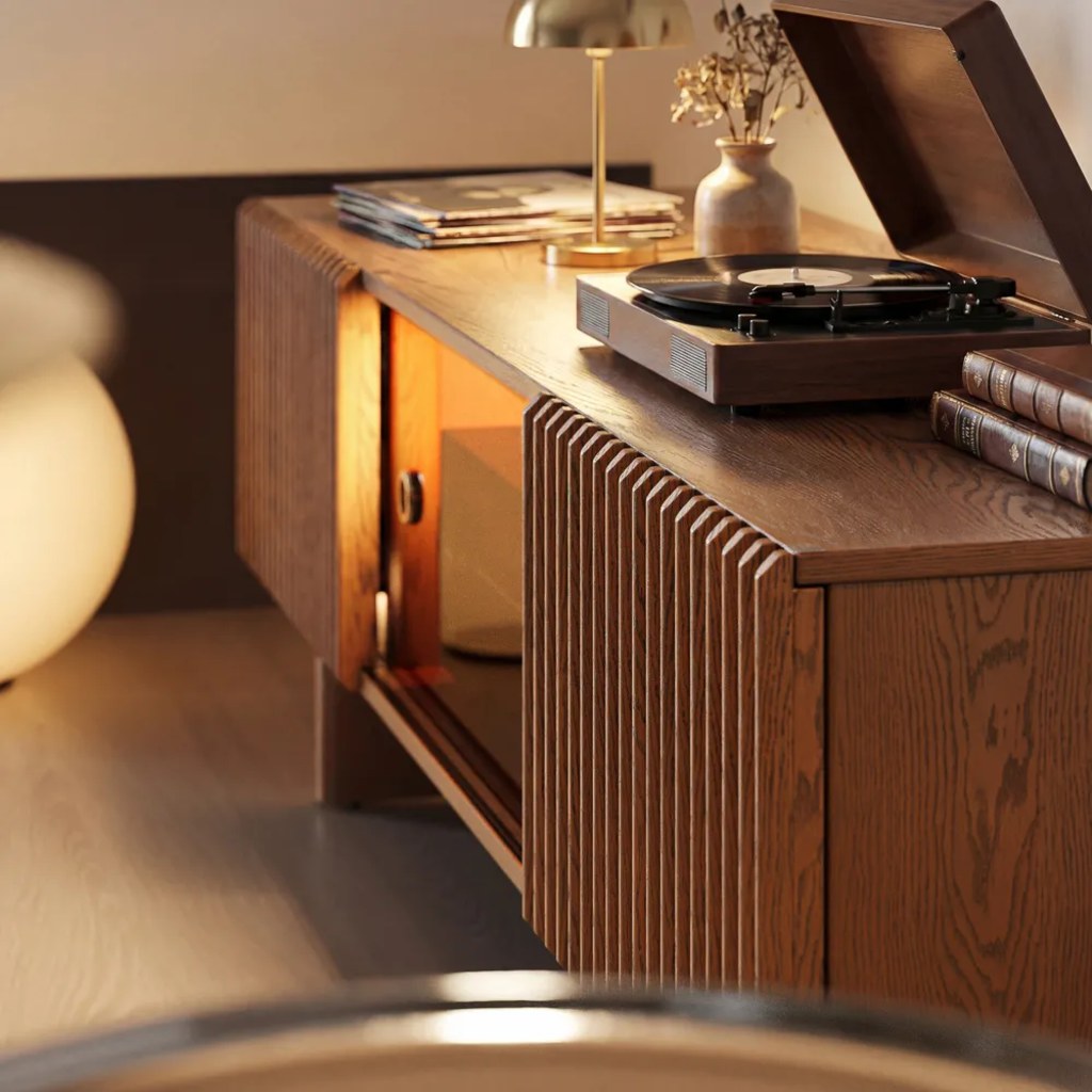 Warm modern living room with a dark wood media console, turntable, brass lamp, books, and open storage.