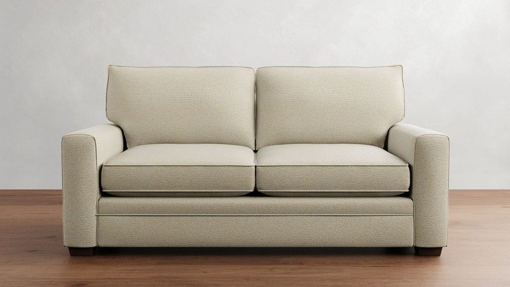 Beige two-seat sofa against a white wall on a wooden floor.