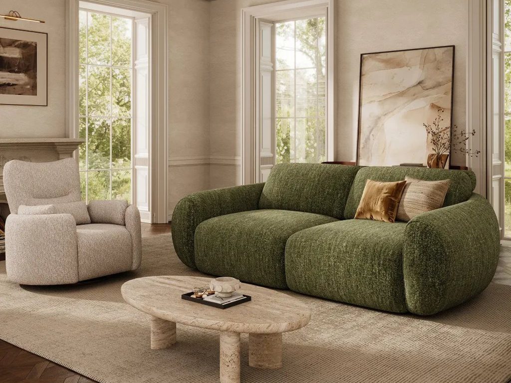 Elegant living room with a deep green curved sofa, cream swivel chair, stone coffee table, large windows, and a glass chandelier.