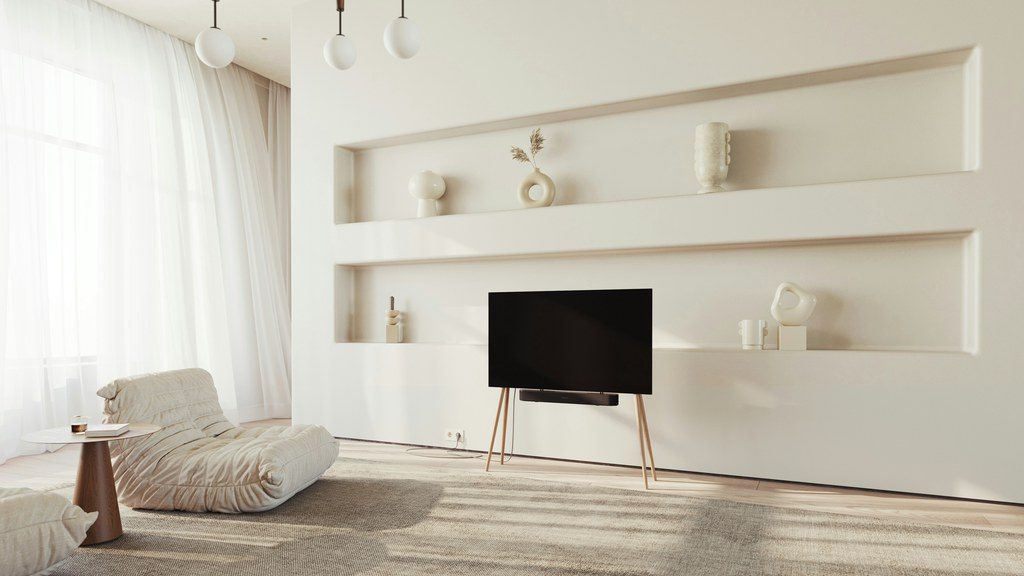 Minimal living room with horizontal wall shelves, floor-to-ceiling curtains, low lounge seating, tripod TV stand, and soft neutral textures.