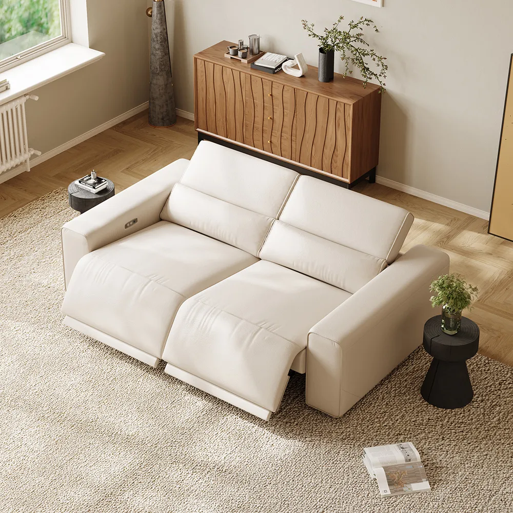 Cream leather reclining sofa in a bright modern living room, styled with warm wood furniture, soft rug, and natural window light.