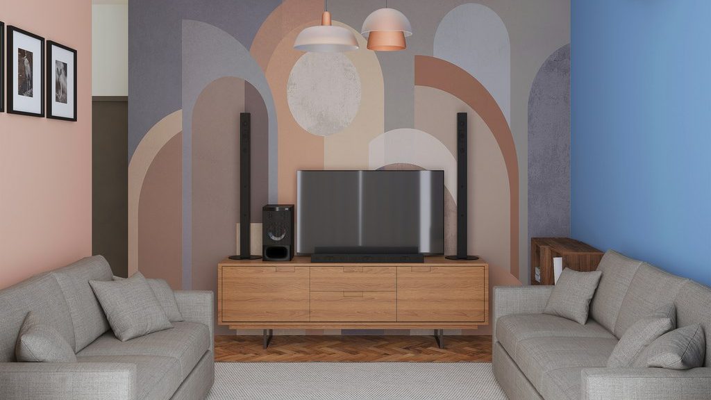Square living room with two sofas facing a TV on a wood media console, framed by a colorful geometric accent wall.